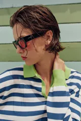 Sweater de punto a rayas horizontales en azul y blanco, con cuello polo verde lima, escote en V y detalles en verde lima en los puños y el borde inferior.