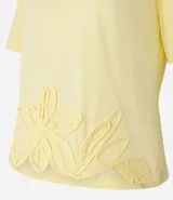 Blusa amarilla de mangas cortas con cuello redondo y bajo con flores bordadas.
