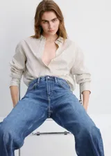 Jeans de denim azul de corte wide leg y tiro medio, con diseño clásico de cinco bolsillos y cierre frontal con botón y cremallera.
