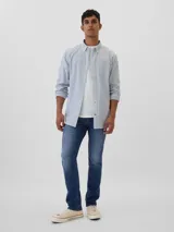 Jean de corte slim athletic en tono azul medio, con diseño de cinco bolsillos, cierre de cremallera y botón metálico.