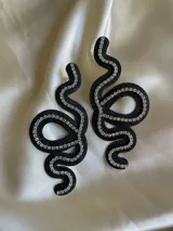 Aros colgantes con forma de serpiente blanca delineada con strass plateado.