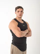 Musculosa negra de corte deportivo con cuello redondo y sisas amplias. Presenta el logo 'GAINS.' bordado en pequeño en el centro del pecho.