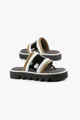 Sandalia con base alta y diseño de líneas audaces. Presenta capellada ancha con acabado brillante y estructura acolchada que aporta confort al andar. La suela dentada le da un carácter urbano y moderno, sin resignar comodidad.