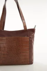 Cartera tipo tote de cuero vacuno negro con doble asa de hombro, panel superior liso y bolsillo exterior frontal con textura símil cocodrilo y costuras visibles en contraste.