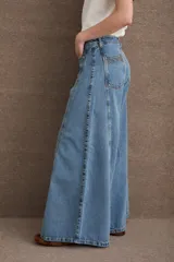 Jean de corte wide leg con tiro alto, confeccionado en denim azul oscuro. Presenta costuras verticales a lo largo de las piernas con pespuntes en color verde a contratono.