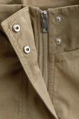 Campera corta de sarga estilo cargo en color verde militar, con cuello elevado, cierre frontal oculto con botones a presión y bolsillos delanteros de gran tamaño con solapa. Presenta diseño oversized con hombros caídos y cordón elástico ajustable en el bajo.