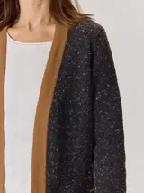 Saco abierto de punto con textura jaspeada en color gris oscuro, con bordes frontales en contraste color marrón. Presenta mangas largas y un corte recto.