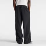 Pantalón de jogging New Balance color negro, de corte holgado y diseño recto. Presenta cintura elástica con cordón ajustable y logo de la marca estampado en la parte superior del muslo izquierdo.
