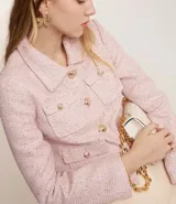 Campera corta de tweed color rosa, con cuello camisero, bolsillos delanteros con solapa y botones dorados estilo escudo.