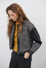 Chaqueta de diseño combinado con paneles de tejido de espiga en tonos marrones y burdeos, y paneles de cuero marrón en mangas y bordes. Presenta cuello redondo, cierre frontal con botones metálicos a presión y bolsillos delanteros.