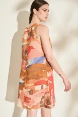 Vestido corto de lino italiano, sin mangas y con cuello redondo, de corte recto y estampado abstracto en tonos tostado, coral, marrón y azul. Cuenta con costuras con detalles desflecados en la parte frontal.