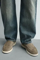Mocasines casuales para hombre, fabricados en piel con acabado en serraje color marrón, de corte liso con detalle de bordón y suela blanca a contraste.