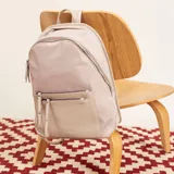 Mochila color beige, combinada con tela tipo impermeable y detalles en simil cuero. Tiene gran tamaño, asas combinadas, bolsillos al frente y compartimiento para notebook de 15".