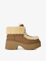 Bota de plataforma con capellada de gamuza color marrón y detalles de piel de oveja en el cuello y la lengüeta. Cuenta con cordones para ajuste y una suela de plataforma de EVA.