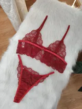 Conjunto de lencería de dos piezas confeccionado en encaje rojo. Incluye un bralette estilo top con breteles regulables y una tanga con laterales ajustables.