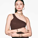 Reloj de pulsera con caja redonda dorada y brazalete metálico dorado adornado con cristales. La esfera es blanca con el logo del cisne a las 12 y tres cristales cuadrados como marcadores de índice. Es sumergible hasta 50 m.