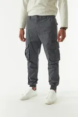 Pantalón cargo gris con puños elásticos, corte regular, bolsillos laterales con solapa y pasacintos.