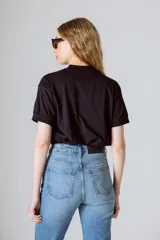 Camiseta básica de algodón orgánico color negro, con cuello redondo alto y mangas cortas con doblez. Incluye un pequeño bordado tono sobre tono de la marca en el pecho.