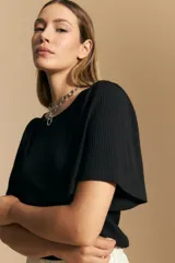 Remera de rib color negro, con cuello redondo, mangas cortas amplias con leve frunce en los hombros y textura elastizada.