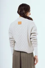Sweater tejido negro de silueta relajada, con cuello alto y textura trenzada.