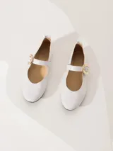 Ballerinas blancas de cuero charol con hebilla dorada y suela negra.