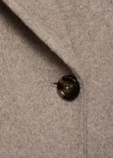 Abrigo largo de diseño oversize confeccionado en tejido con mezcla de lana. Presenta cuello con solapas de muesca, cierre frontal de doble botonadura y hombros caídos. Cuenta con dos bolsillos laterales y abertura posterior en el bajo.