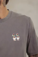 Remera color durazno de corte recto y manga corta, con cuello redondo y pequeño bordado de dos patos en el pecho.