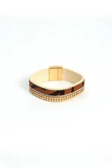 Brazalete ancho con estampado animal print y detalles de cadenas doradas y strass. Cierre magnético.
