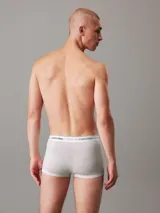Pack de tres bóxers tipo trunk Calvin Klein de talle bajo, confeccionados en mezcla de algodón y elastano. Incluye uno en color azul, uno gris y uno negro con monogramas estampados. Todos cuentan con cinturilla elástica blanca con el logo de la marca.
