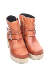 Bota corta color marrón de cuero liso, con caña baja, base beige y dos correas con hebillas plateadas.