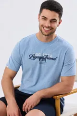 Remera azul marino de manga corta con cuello redondo, confeccionada en mezcla de algodón y poliéster. Presenta un diseño en el frente que combina estampa y bordado con la leyenda "Legacy Brand 1972" en tonos rosado, verde y marrón.