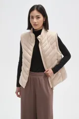 Chaleco acolchado de diseño capitoneado con cierre frontal y bolsillos laterales. Presenta un cuello alto y detalles de botones metálicos decorativos.