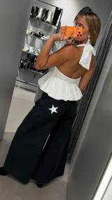 Top blanco con escote halter profundo y diseño peplum fluido, con corte ajustado en el busto y vuelo inferior.