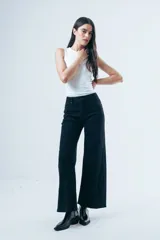 Jean de corte wide leg y tiro alto, color negro, con paneles laterales en el ruedo que aportan mayor amplitud y movimiento.