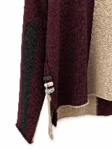 Polera de tejido lambswool con diseño bicolor en tonos neutros. Presenta cuello alto tejido, mangas largas con franjas laterales en color marrón y detalle de bordado artesanal con tres pequeñas líneas horizontales en colores vibrantes.