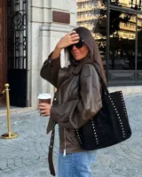 Cartera tipo tote bag color negro de símil gamuza con detalles de tachas plateadas en los bordes y asas dobles para el hombro.