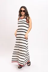 Vestido largo de punto con diseño de rayas en zigzag de color blanco y negro, sin mangas, con ribetes en tono bordó en el cuello y las sisas, y aberturas laterales en el bajo.