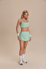 Pollera deportiva color rosa fucsia, con estampado en relieve de texto. Es de corte corto con ruedo redondeado y cuenta con shorts internos.