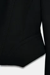 Blazer corta negra de la colección Zara Woman, con cuello solapa de muescas y manga larga. Presenta detalles de pespuntes marcados y forro interior a tono. Cierre frontal con botones.