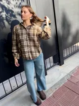 Camisa de corte holgado con estampado de cuadros escoceses en tonos beige y marrón. Presenta cuello clásico, cierre frontal con botones y mangas largas.