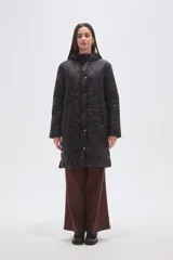 Campera acolchada de largo medio en color negro, con diseño de costuras onduladas, cierre frontal con botones a presión y bolsillos laterales.