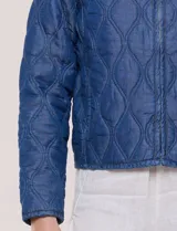 Campera corta azul de lyocell con acabado matelaseado en patrón de ondas, escote redondo, cierre frontal con cremallera y manga larga.