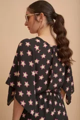 Blusa negra con estampado de estrellas color beige con contorno fucsia, mangas cortas amplias y escote redondo.