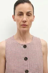 Chaleco de corte sastre con escote en V y cierre frontal con botones oscuros. Presenta un diseño de estampado a cuadros pequeños en tonos beige y rojizos.