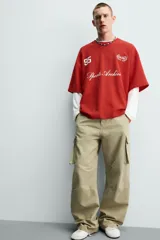 Camiseta relaxed fit de color rojo, cuello redondo y manga corta. Presenta estampados y bordados combinados a contraste en el delantero con inscripciones y el número 95.