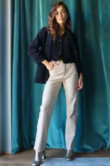 Pantalón de cuerina color beige, de corte recto y tiro alto, con detalle de costuras verticales en el frente.