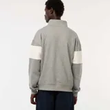 Buzo gris con cuello alto y cremallera parcial, con franja blanca horizontal en el pecho con la inscripción "New York Upper East Side" en azul marino.