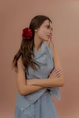 Chaleco de lino color marfil o beige claro, con diseño sin mangas, cuello alto amplio, cierre frontal con botones y bolsillos delanteros amplios. Presenta un corte asimétrico y relajado.