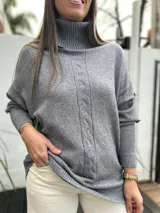 Sweater de punto gris con cuello alto, diseño de trenza vertical en el centro y mangas largas con puños acanalados.