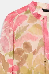 Blusa de manga larga con estampado floral en tonos rosados, verdes y beige. Presenta escote en pico con detalle de abalorios colgantes y cierre frontal con botones.